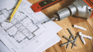 Perceuse, visserie et plan technique sur un bureau de chantier pour des travaux de rénovation énergétique dans un bâtiment tertiaire