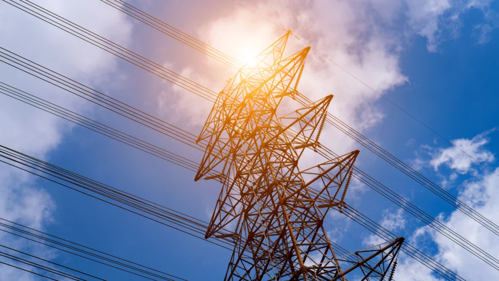 Pylône électrique sous un soleil intense, illustrant la tension sur le réseau en période de canicule.
