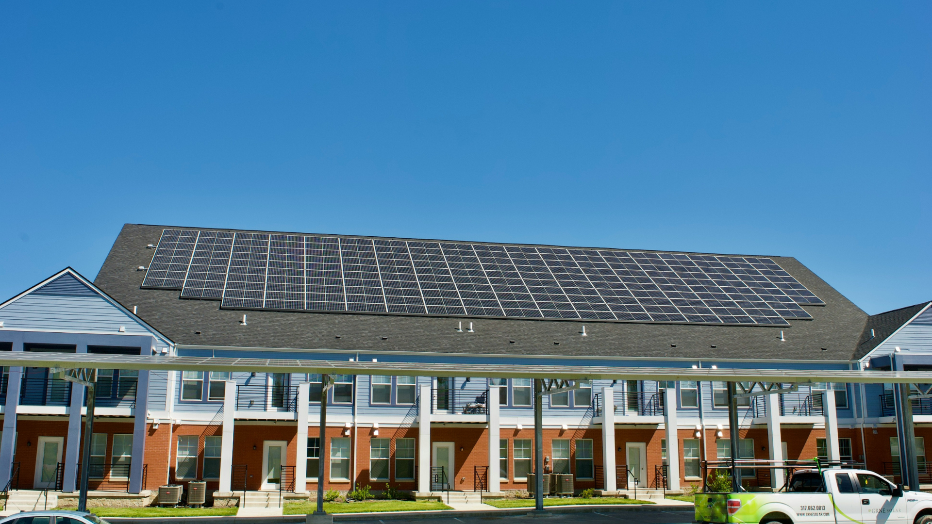 Panneaux solaires photovoltaïques en toiture et ombrières de parking équipant un bâtiment